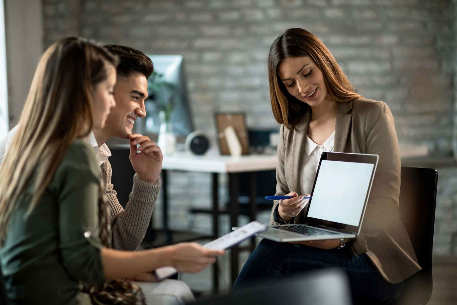 Mulher jovem e bonita apresentando um trabalho em seu laptop para um casal de clientes